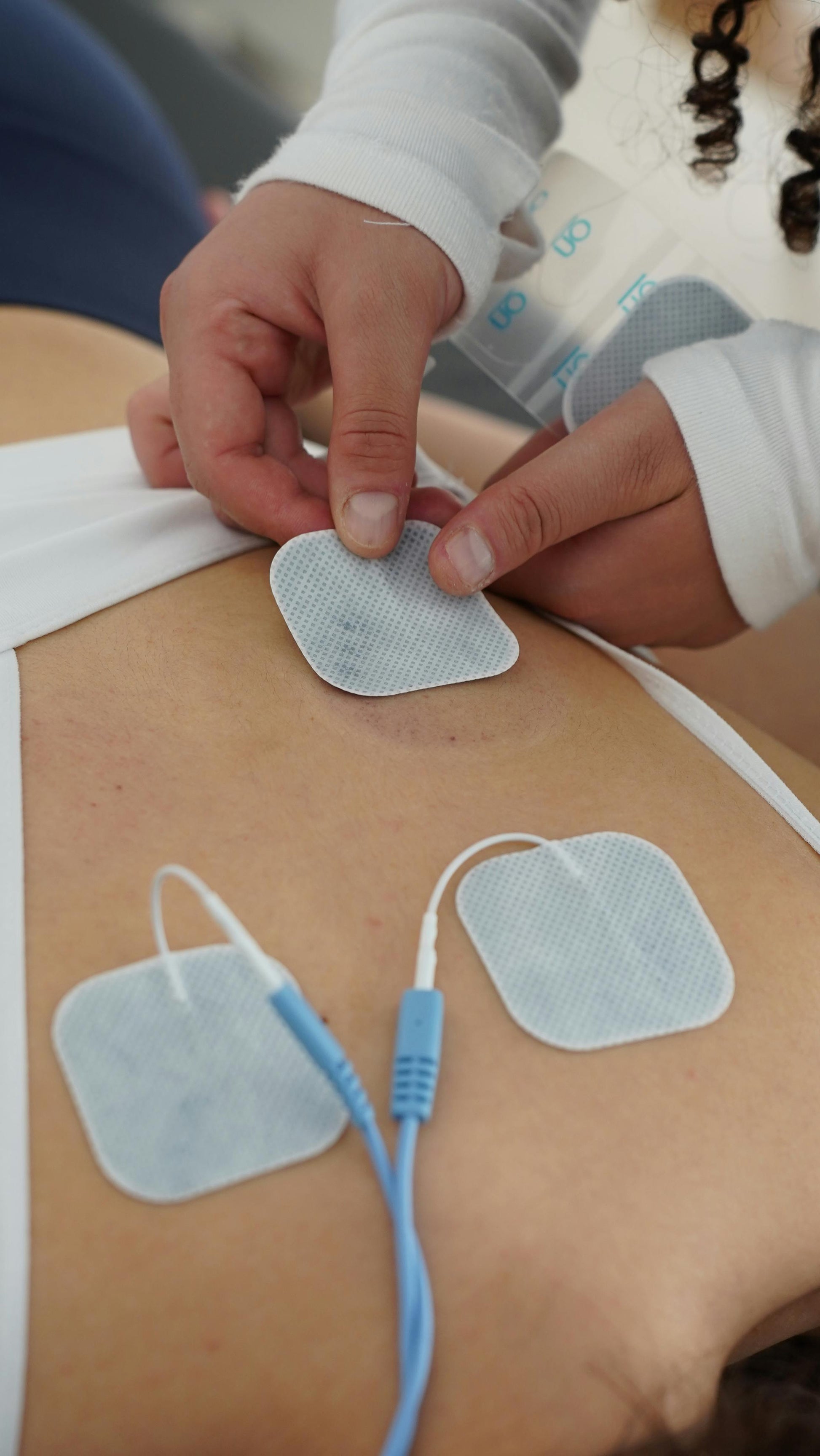 Physiotherapy session using TENS electrotherapy pads on back for pain relief