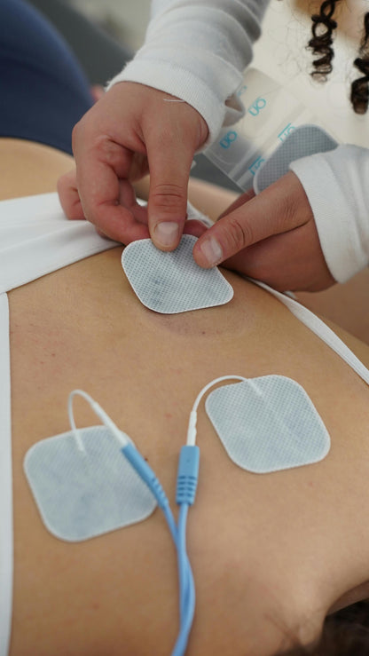 Physiotherapy session using TENS electrotherapy pads on back for pain relief